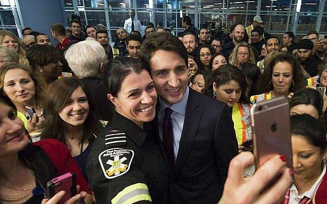 Canadian Prime Minister Justin Trudeau poses for a selfie with workers before he greets new immigrants at Pearson International airport. (Nathan Denette/The Canadian Press via AP)